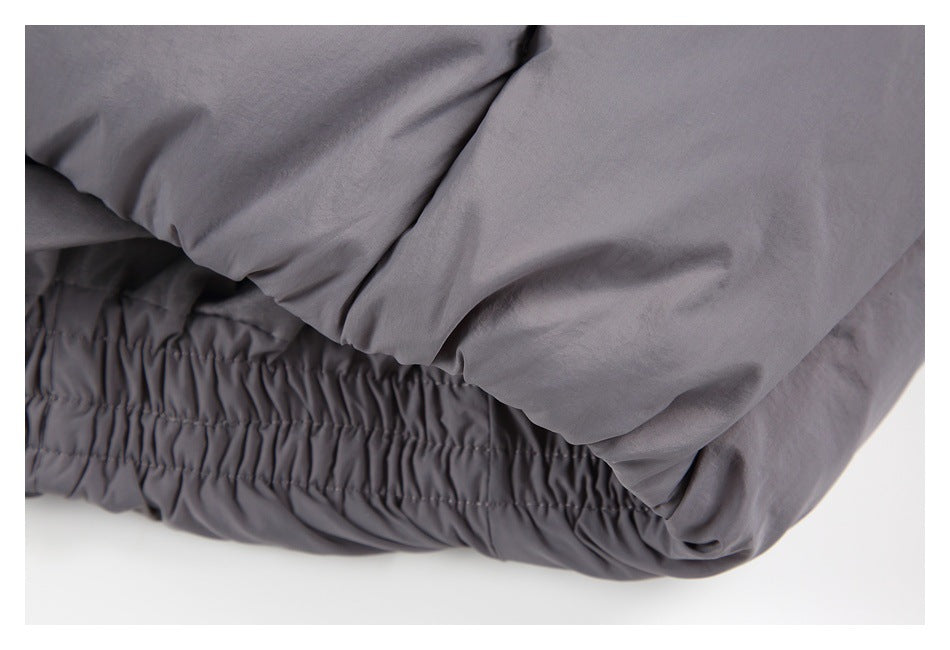 Close-up of the elasticated hem and quilted panels of a gray puffer jacket.