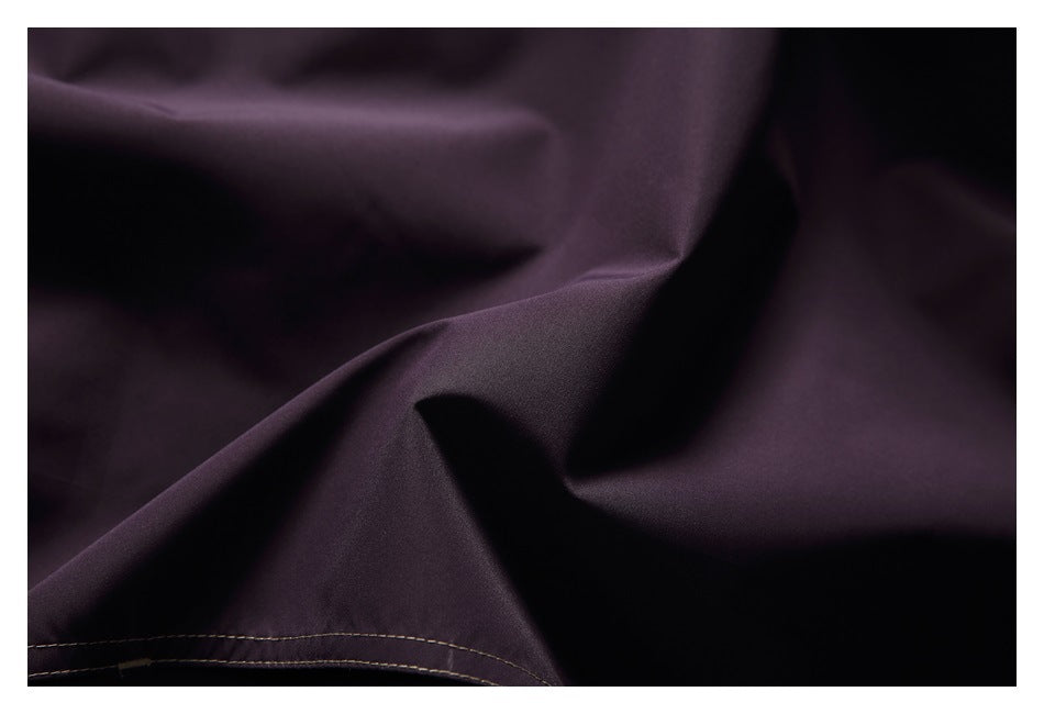 Close-up of dark plum fabric folds with a double-stitched hem.