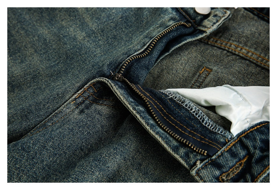 Close-up of blue-wash jeans with the front fly unzipped, showing the zipper, stitching and inner lining.