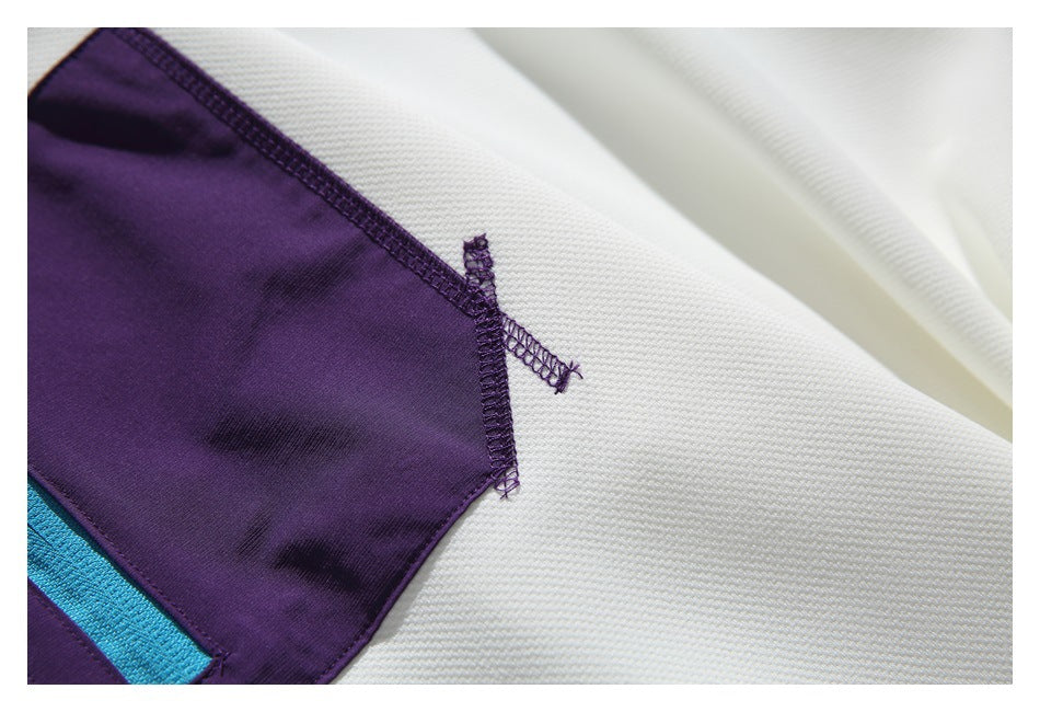 Close-up of the purple pocket edge and stitching against the white sweatshirt fabric.