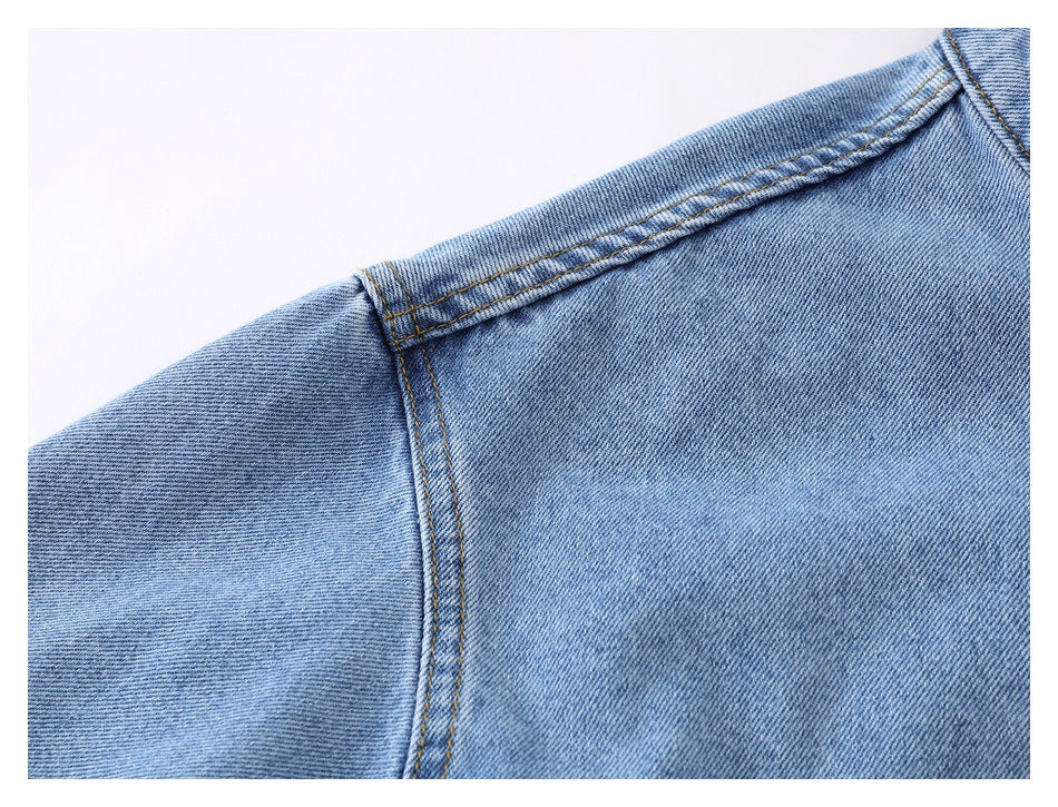 Close-up of the light blue denim jacket shoulder seam and contrast stitching.
