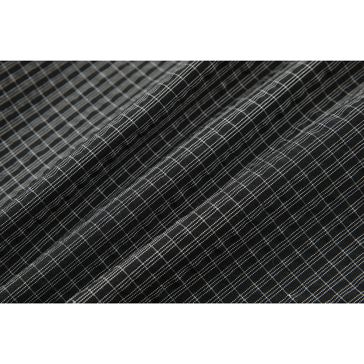Macro view of the dark fabric's fine gray plaid pattern.