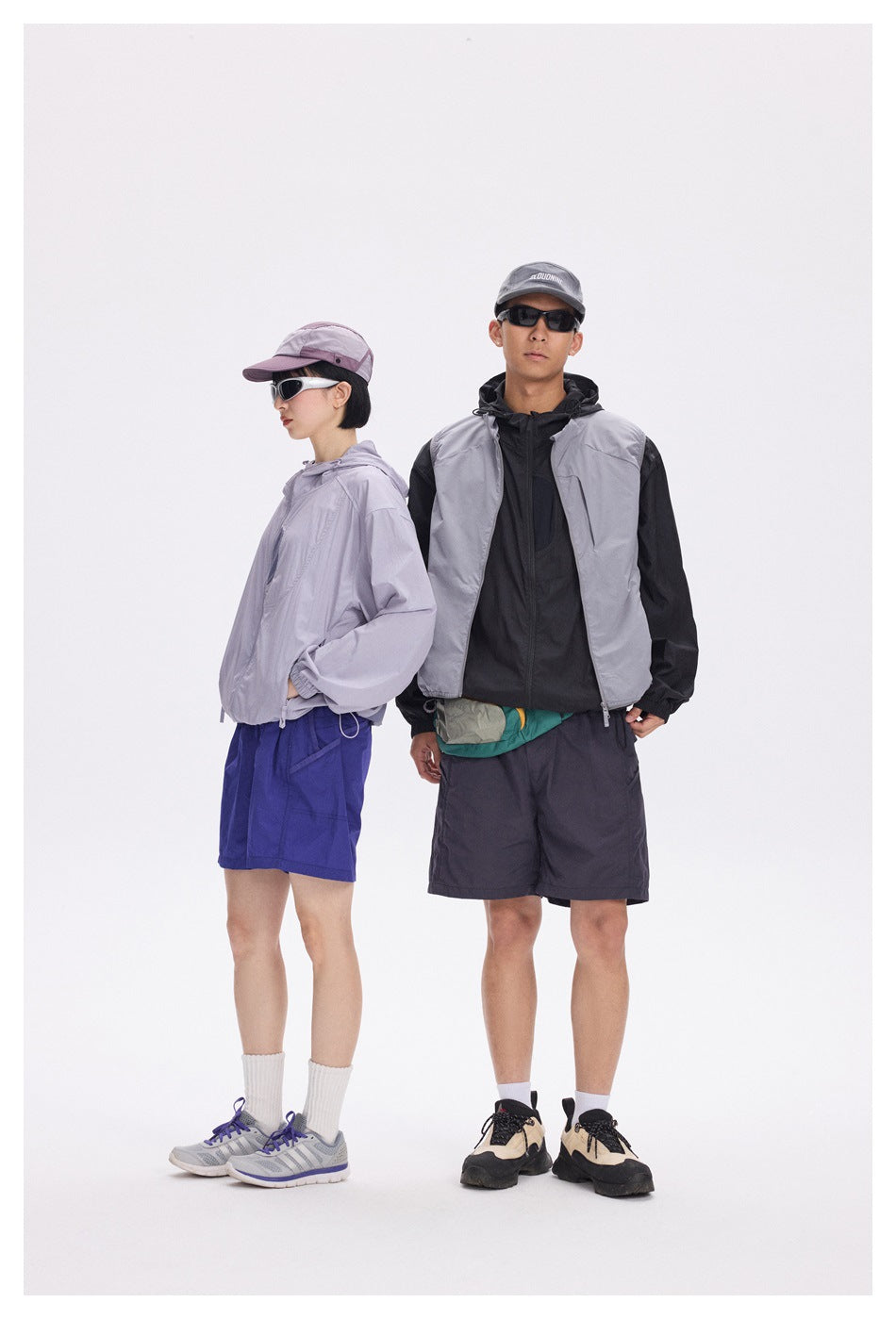 Two models pose in outdoor-style outfits: a lavender jacket with blue shorts and a gray-and-black jacket with dark shorts.