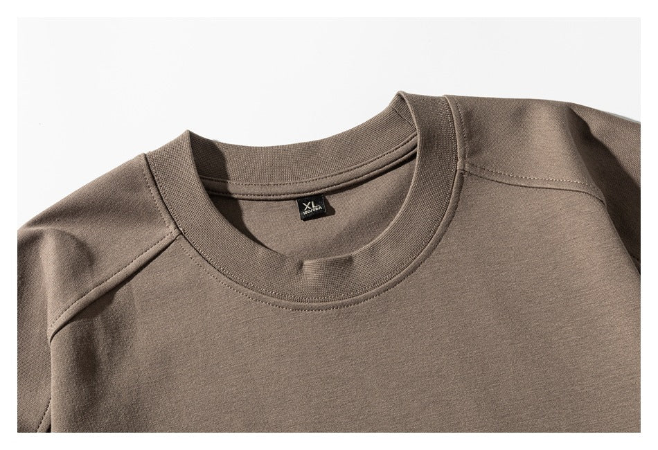 Close-up of a taupe sweatshirt's crewneck, shoulder seams, and small black size label.