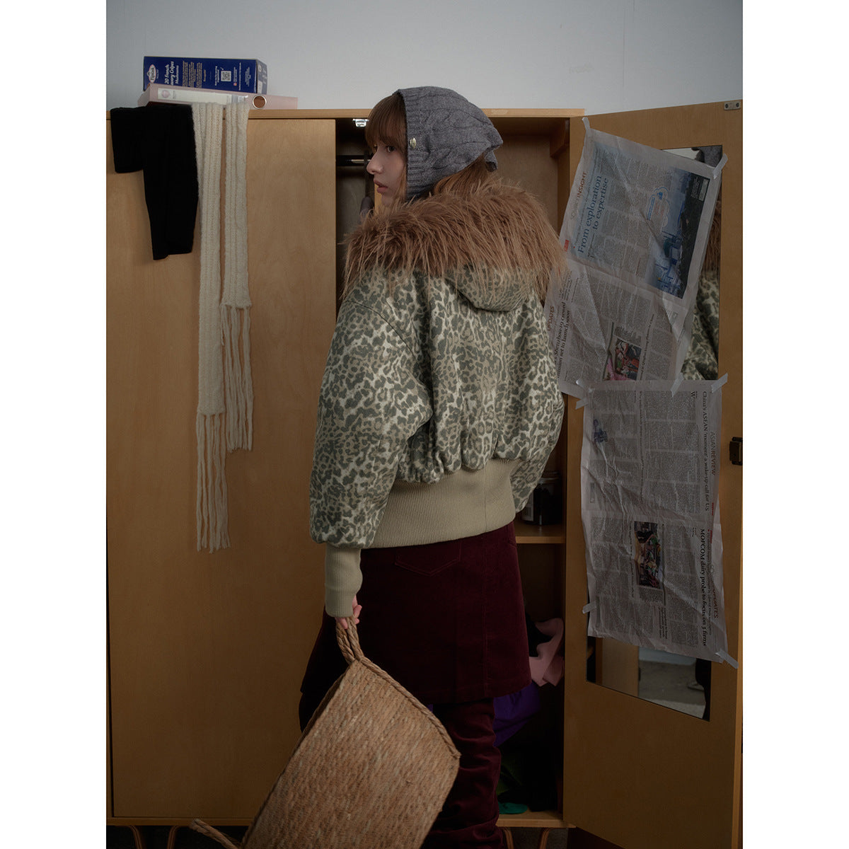 Side and back view of a model in a gray leopard-print jacket with a brown fur-trimmed hood and ribbed beige hem.
