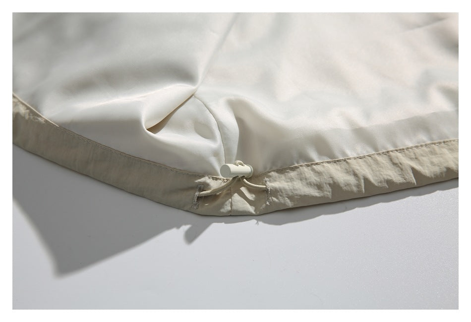 Close-up of an ivory garment hem with a drawcord and toggle.
