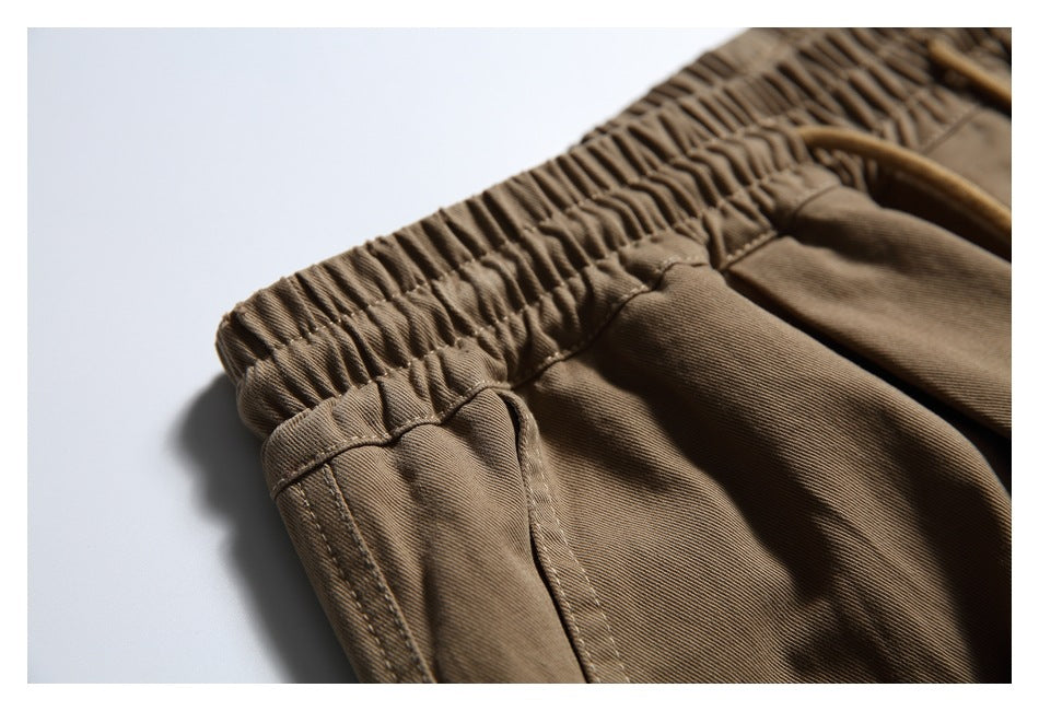 Close-up of brown pants showing the gathered elastic waistband and stitching around a side pocket opening.
