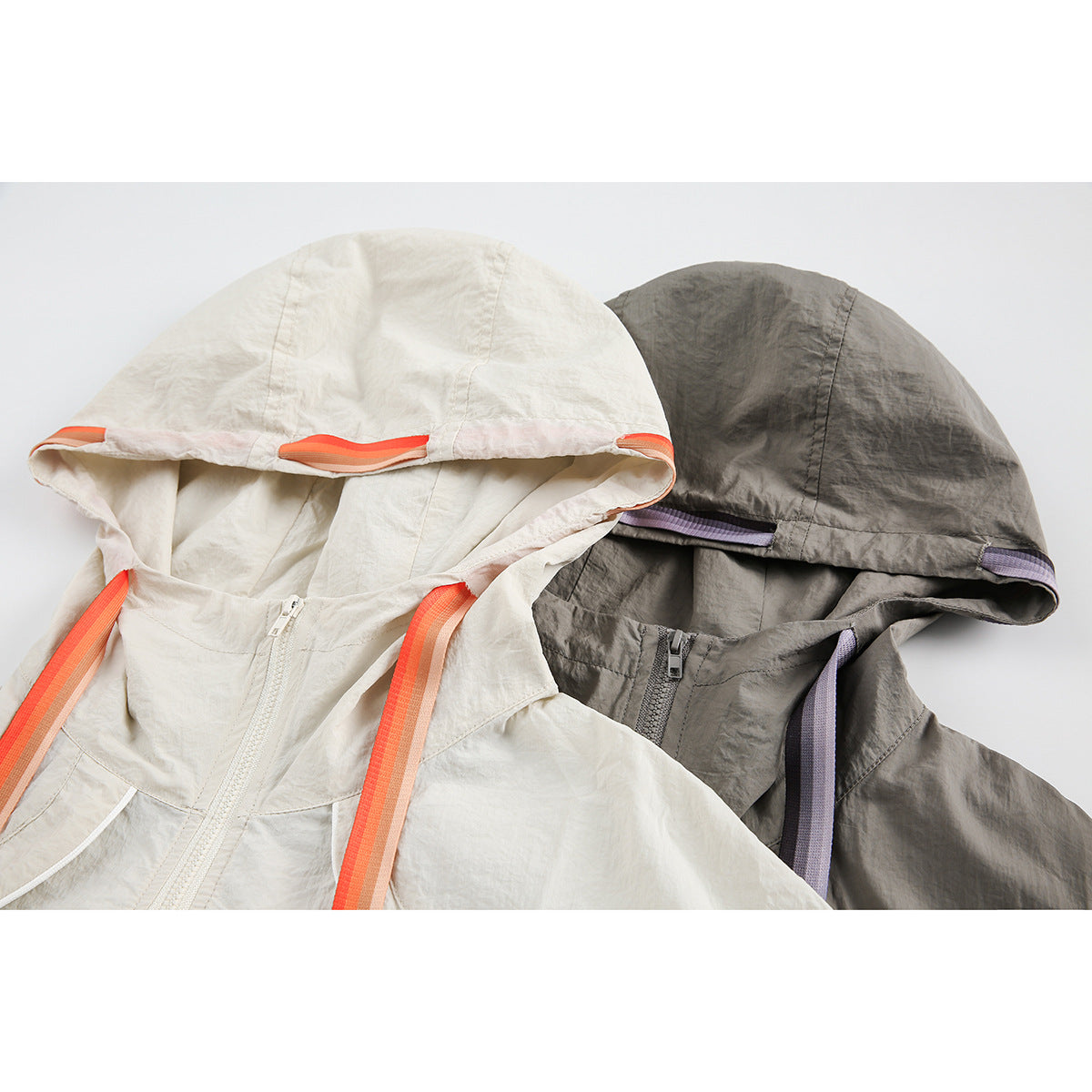 Close-up of ivory and gray hooded jackets showing the hoods, zippers and bright contrasting trim.