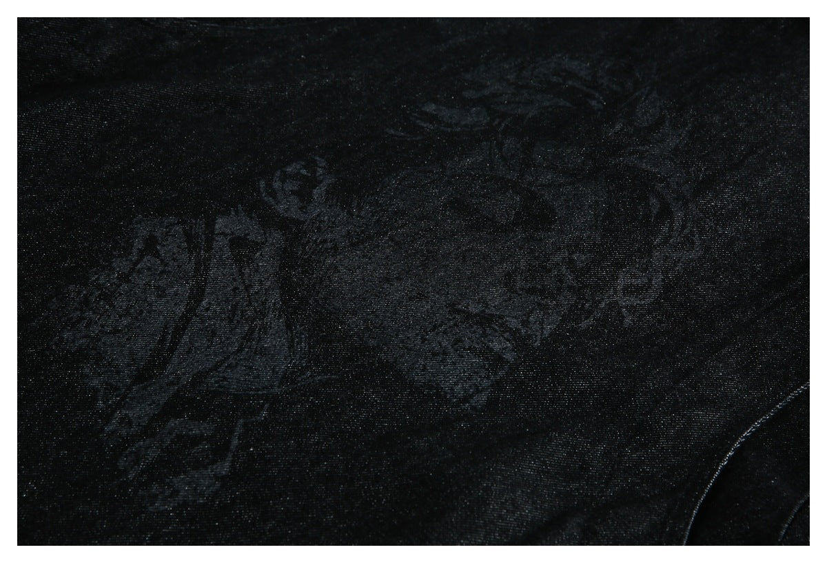 Close-up of black fabric with a faint, low-contrast tonal illustration or pattern.