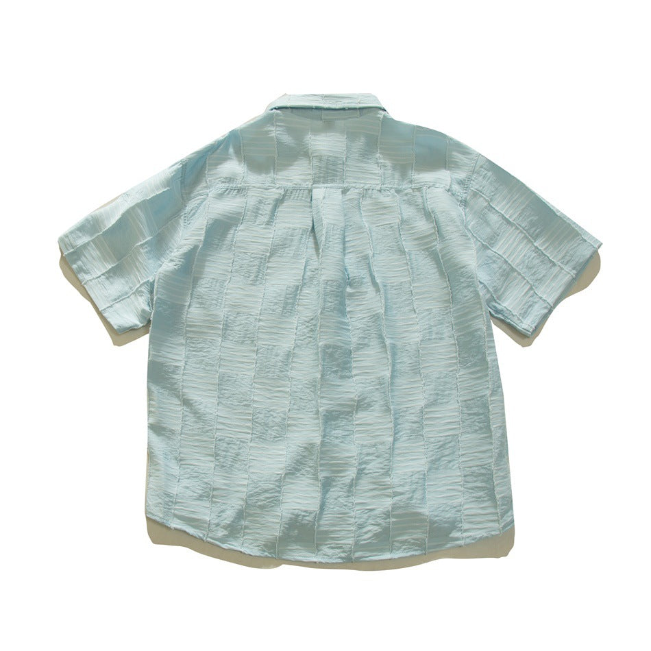 Back view of a pale blue short-sleeved button-up shirt with textured panels and a straight collar.