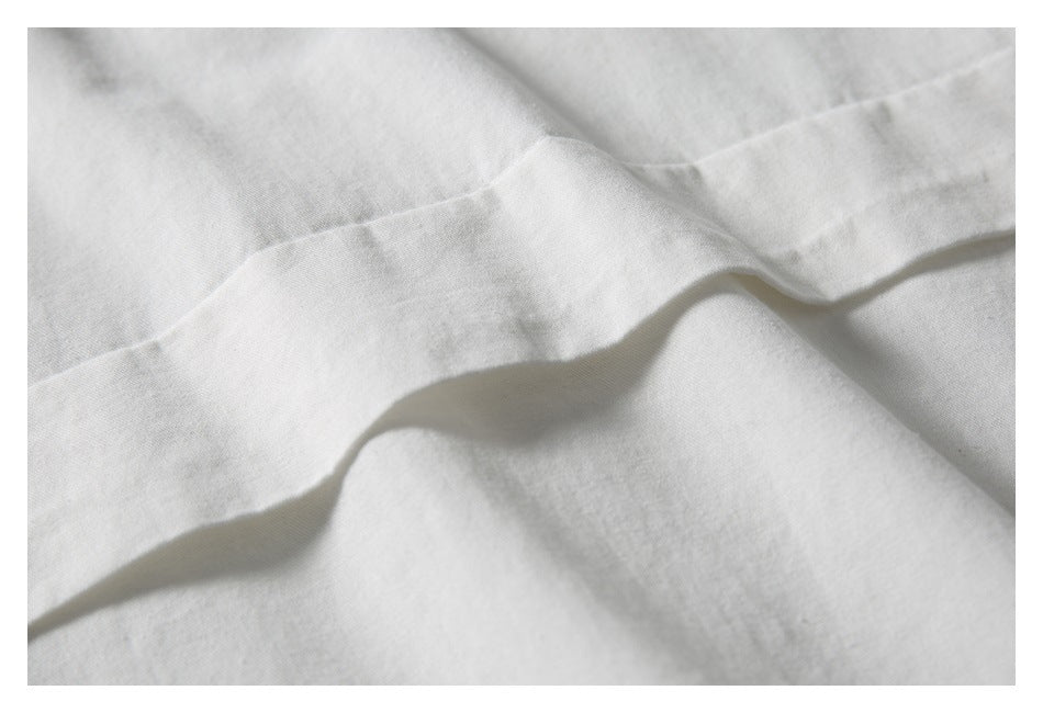 Close-up of a white garment's stitched fabric edge and soft folds.