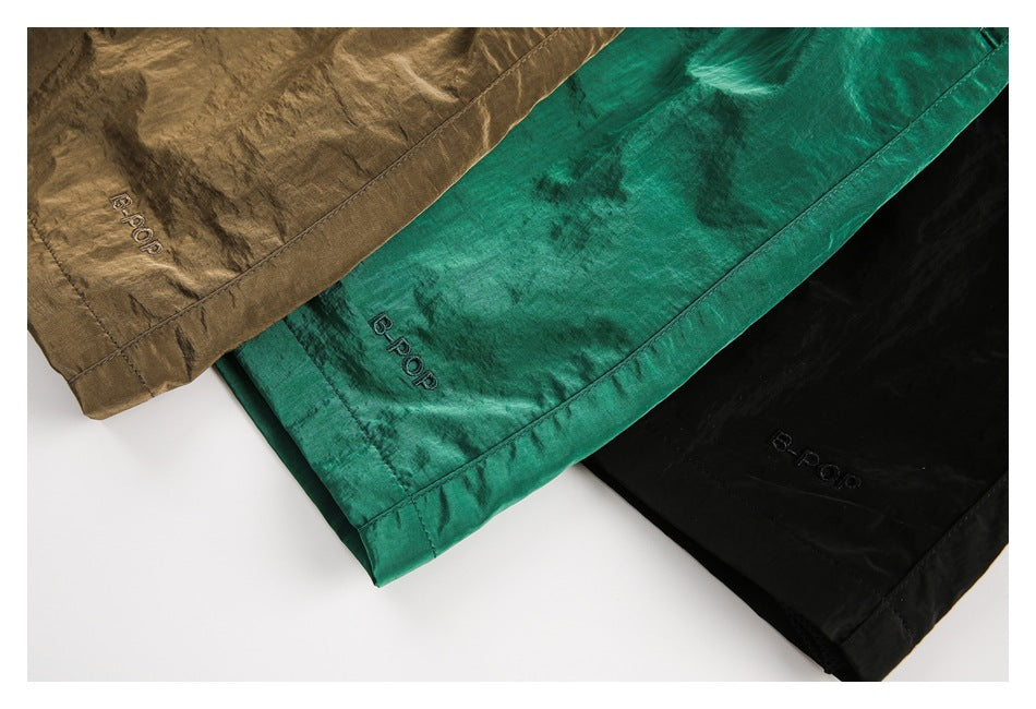 Close-up of brown, emerald green, and black shorts hems with embroidered B-POP lettering.