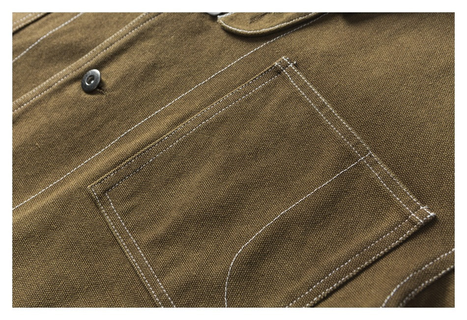 Close-up of a rectangular chest pocket with contrast stitching on the brown jacket, beside a front button.