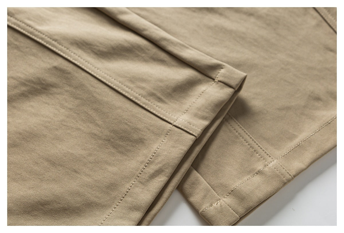 Close-up of tan trouser fabric with stitched hems and folded edges.