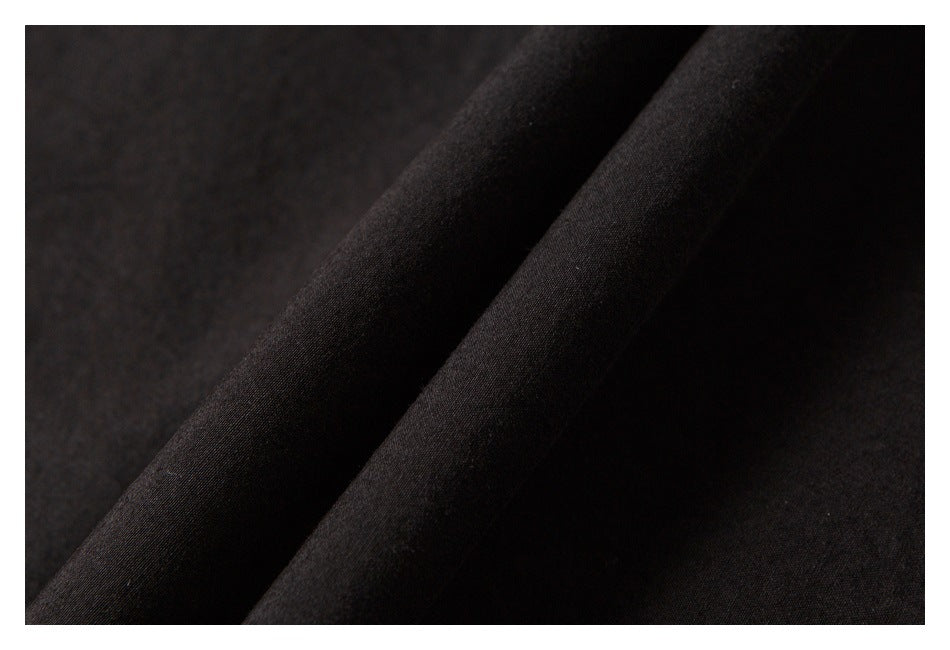Extreme close-up of dark fabric draped into folds, showing its fine surface texture.