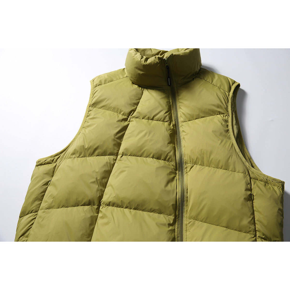 Close-up of an olive-green quilted puffer vest front with a tall stand collar and offset zipper.