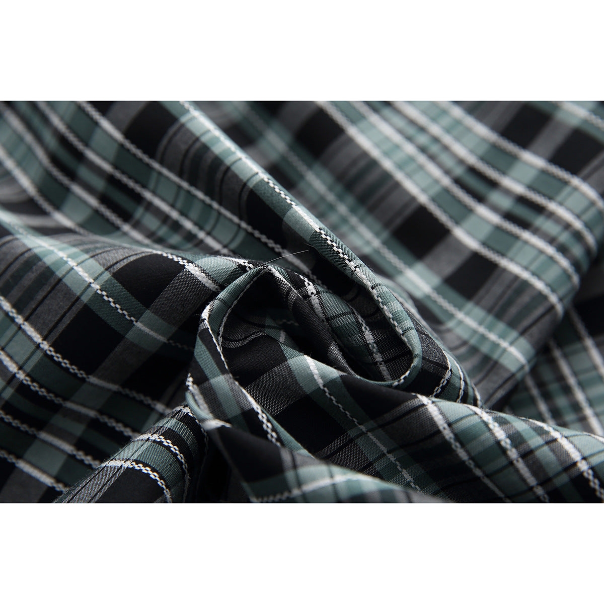 Close-up of the black, gray, and muted green plaid fabric and its woven-looking grid pattern.