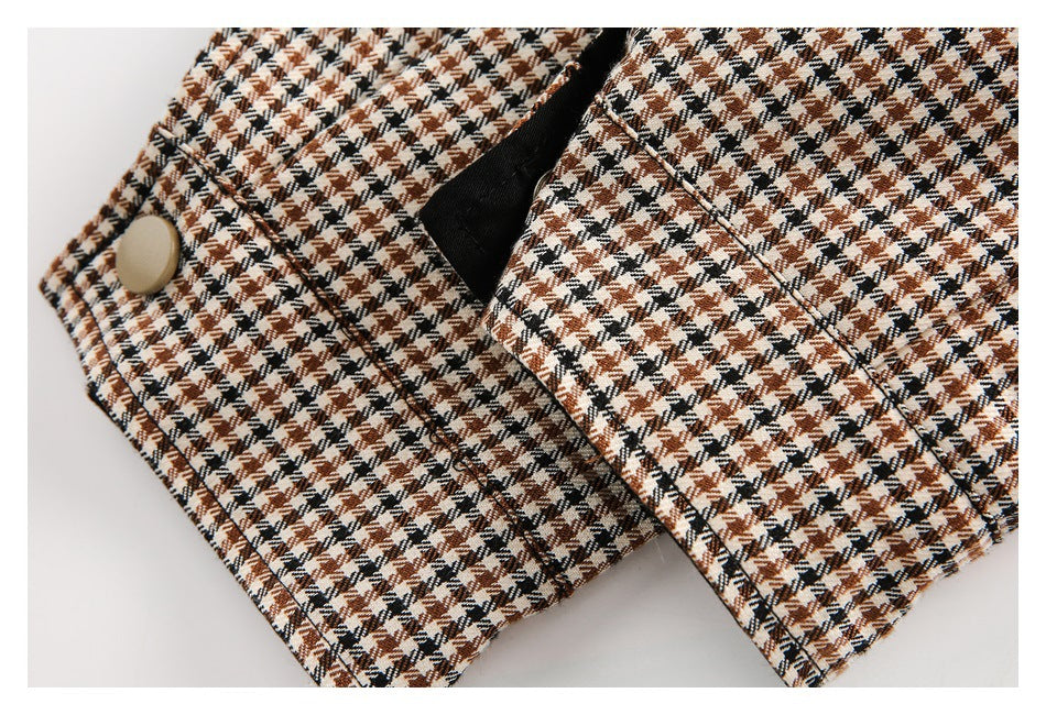 Close-up of a beige button and stitched fastening on brown, black, and cream houndstooth fabric.