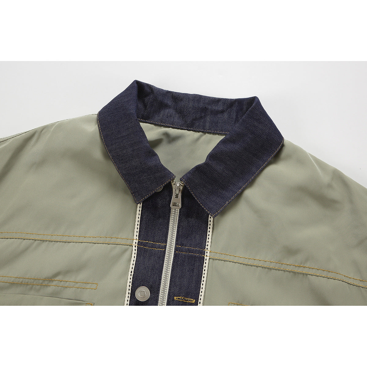 Close-up of an olive jacket’s dark denim collar, zip-front placket, contrast stitching and snap button.