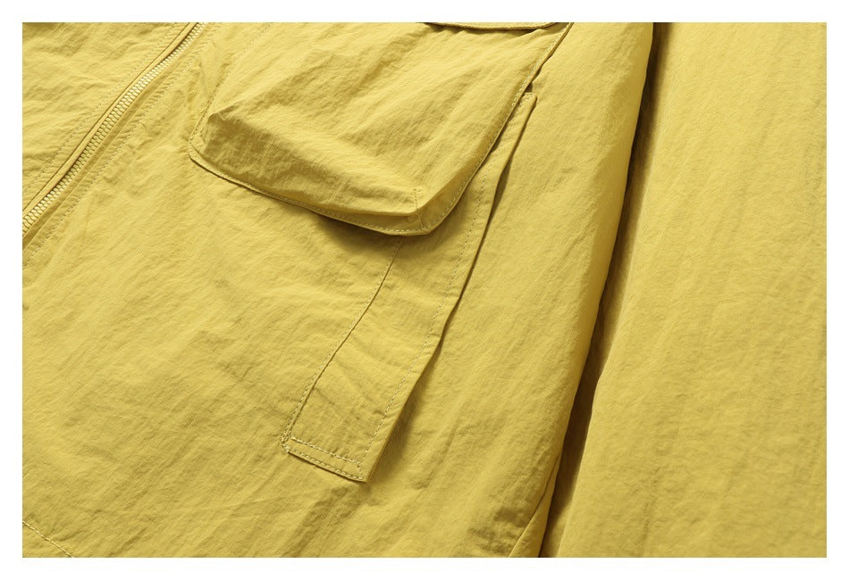 Close-up of the yellow jacket's lower pocket edge and stitched side panel.
