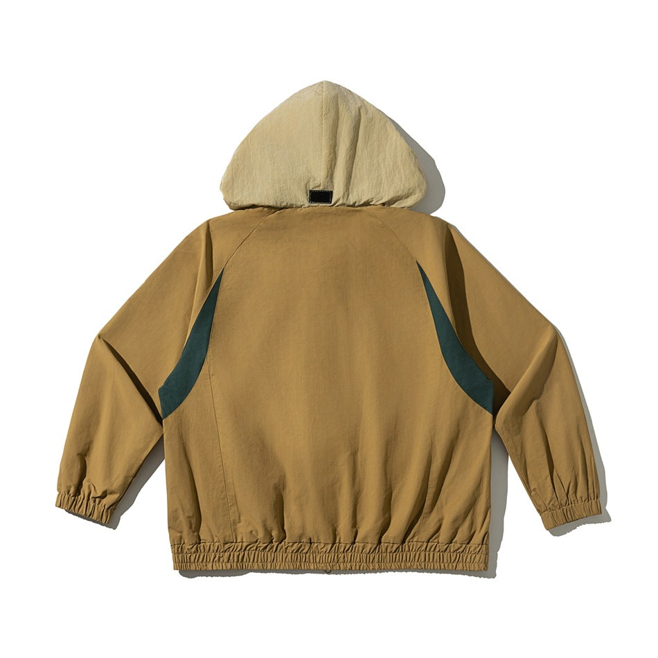 Back view of a tan hooded jacket laid flat, with dark teal side panels and elastic cuffs and hem.