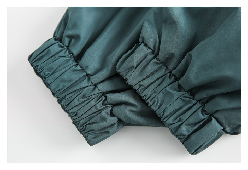 Close-up of gathered elastic cuffs on a teal garment.