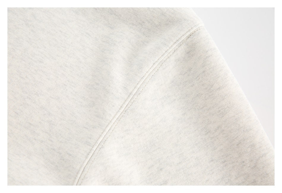 Close-up of an ivory heather sweatshirt seam and soft-looking surface.