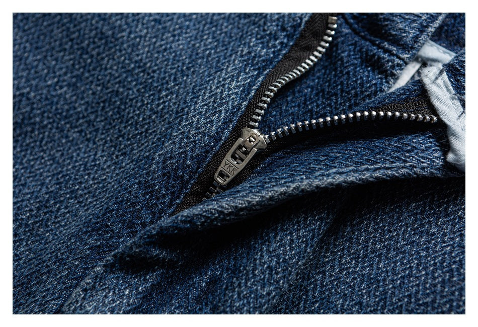 Close-up of a metal zipper on dark blue denim; the zipper pull is marked YKK.
