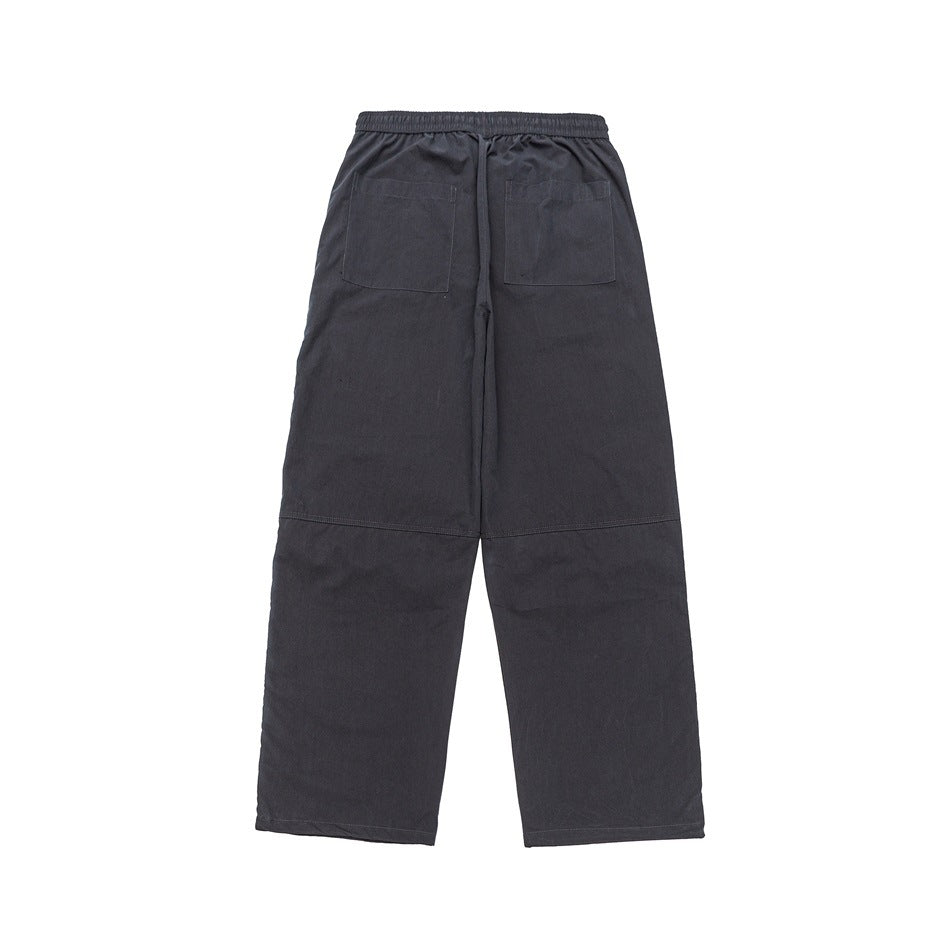 Back view of charcoal wide-leg pants with an elastic waistband, two patch pockets, and seam details.