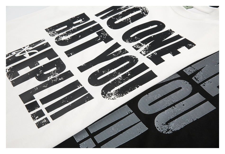Close view of white and black T-shirts with large distressed black lettering.