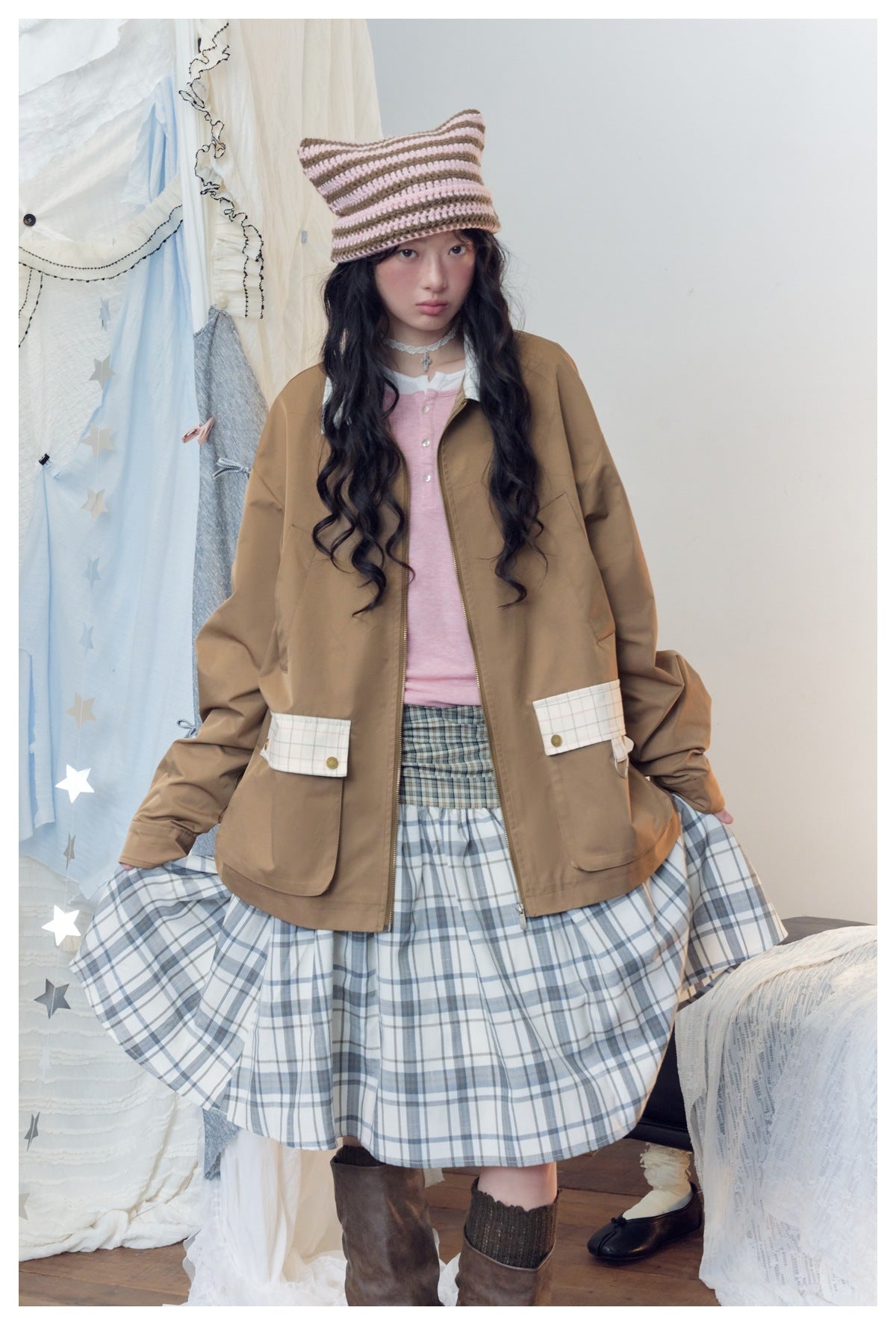 Model wears a brown jacket with plaid pocket flaps over a pink top and blue-gray plaid skirt.