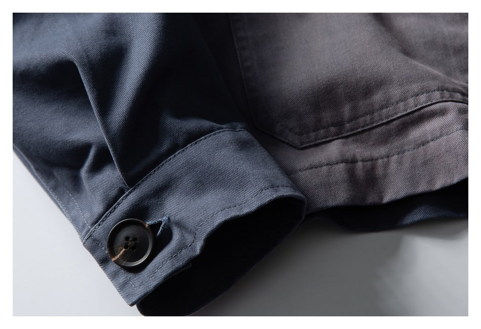 Close-up of a gray jacket sleeve cuff with a dark button and stitched seam details.