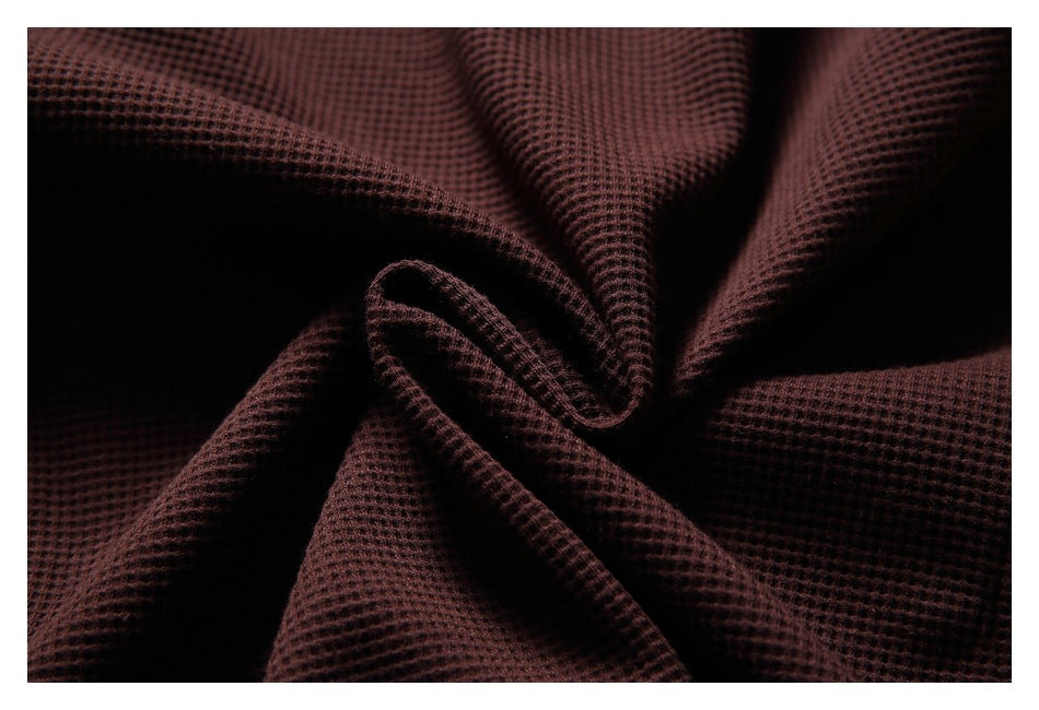 Macro view of burgundy waffle-knit fabric gathered into folds.