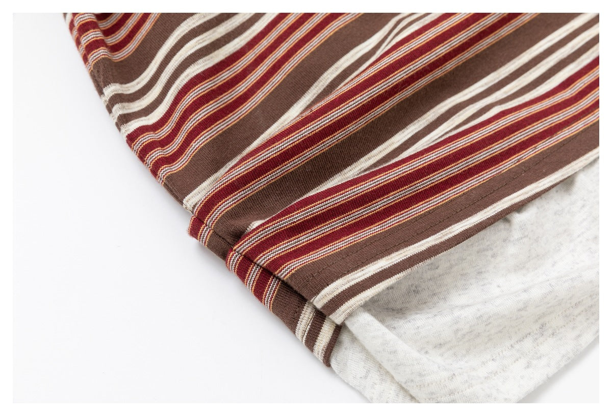 Close-up of the folded hem of a brown, burgundy, and cream striped top, showing the light gray underside.