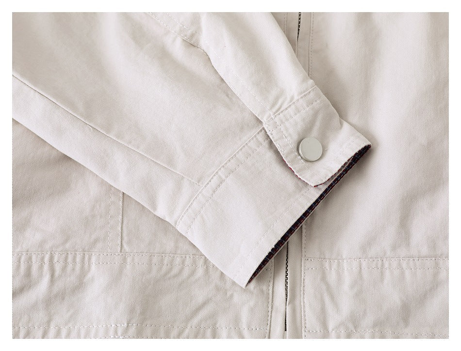 Close-up of a beige jacket sleeve cuff with a metal snap and a glimpse of plaid lining.