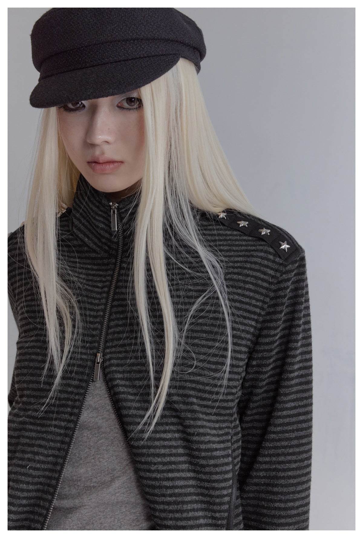 Close-up of model wearing the striped stand-collar jacket, with star studs on the shoulder and a partly open zipper