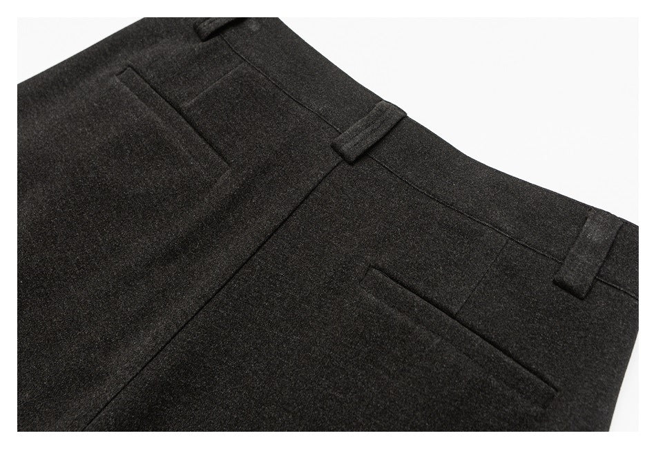 Close view of charcoal trousers showing the waistband, belt loops, and two welt pockets.