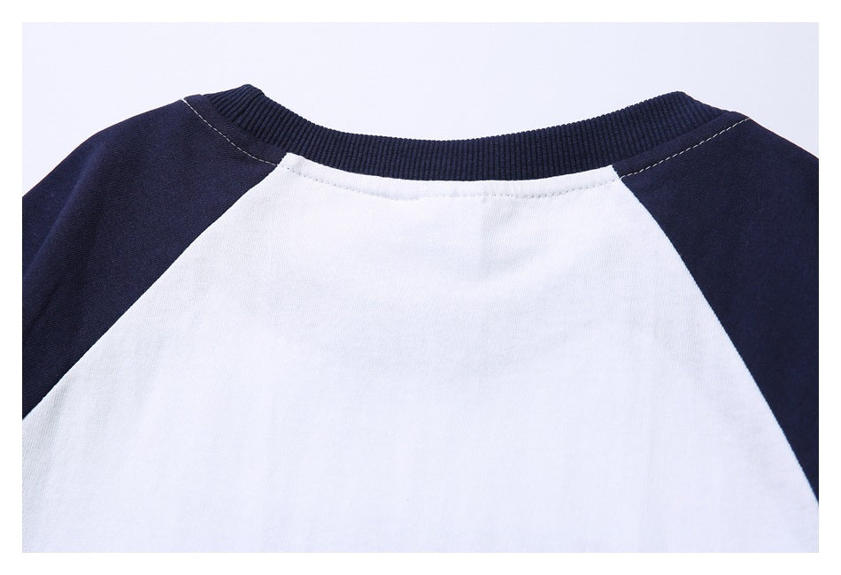 Close-up of a white shirt neckline with a ribbed navy collar and navy raglan sleeves.