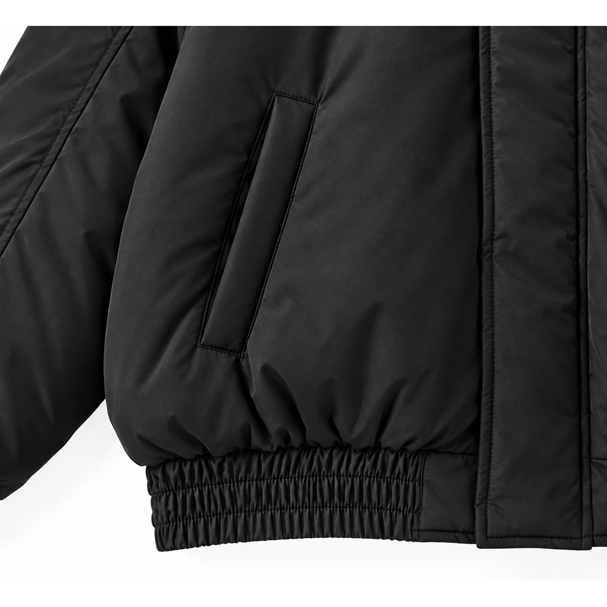 Close-up of the black jacket's angled pocket, smooth fabric and gathered elastic hem.