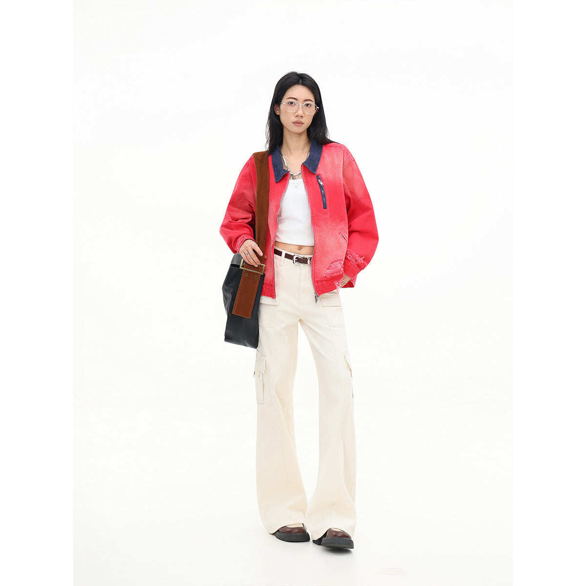 Model wearing a coral-red zip jacket with a dark blue collar and distressed hem, paired with cream cargo pants.
