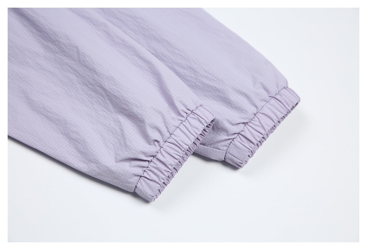 Close-up of two elasticated cuffs on lavender grid-patterned garment legs.