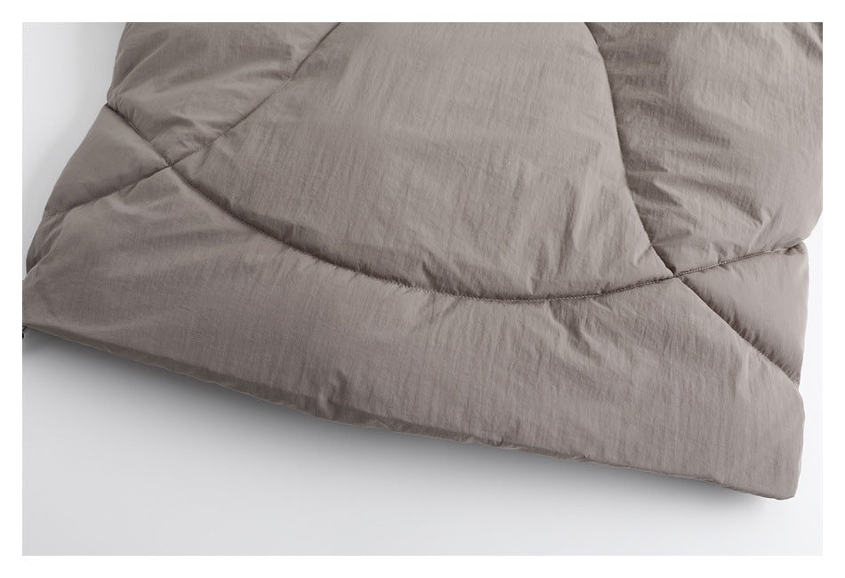 Close-up of curved quilting and panel seams on the taupe padded jacket.