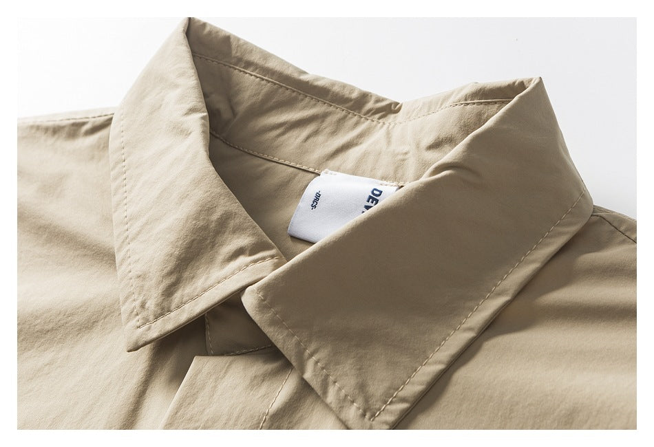 Close-up of the beige shirt's pointed collar, stitching, and interior neck label.