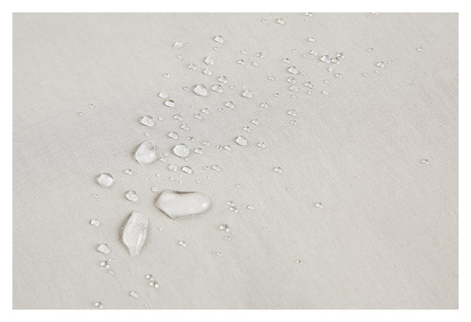 Water droplets bead on the surface of light beige fabric.