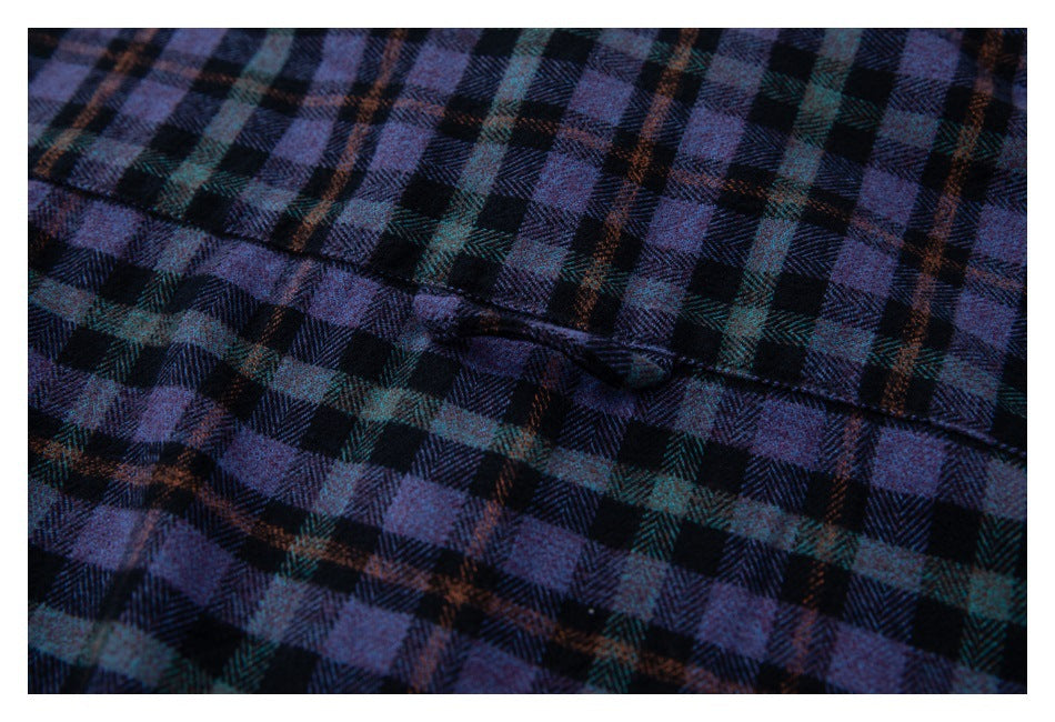 Close-up of dark purple plaid fabric showing a stitched seam and small buttonhole.