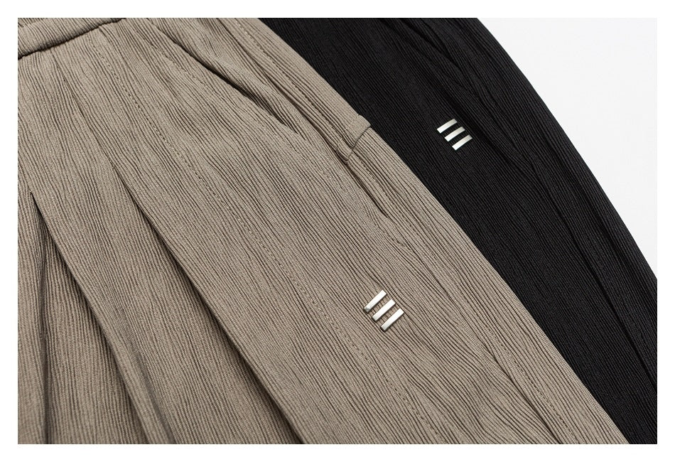 Close-up of taupe and black ribbed pants, each with a small three-bar detail.