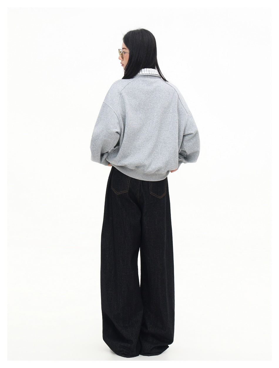 Rear view of a model wearing a light gray pullover with a patterned collar and wide-leg black jeans.