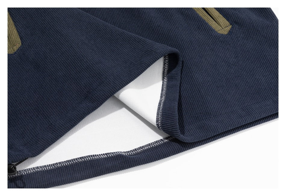 Close-up of a navy ribbed garment hem with visible overlock stitching and partial tan trim.