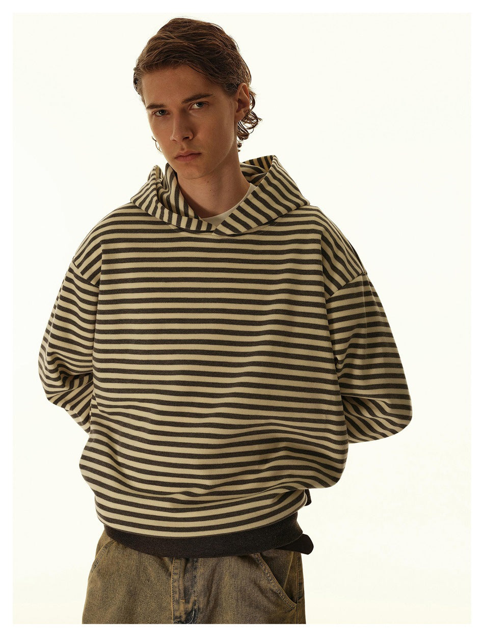 Model wearing a striped hooded sweatshirt with drop shoulders over a tee, with washed jeans, close-up front view