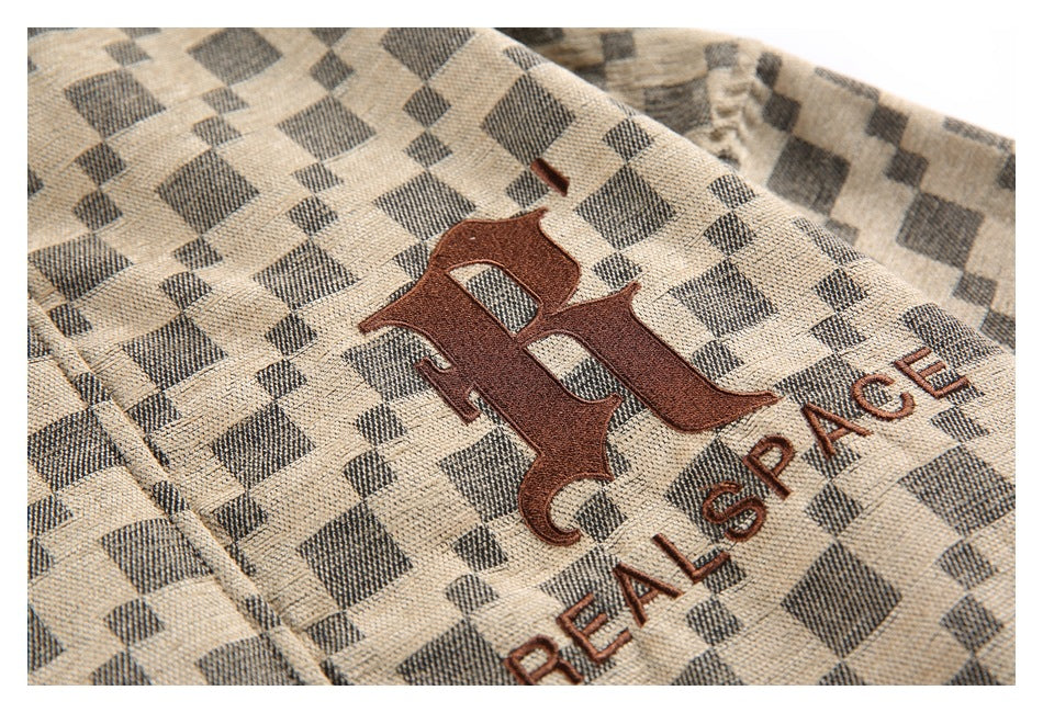 Close-up of a brown embroidered emblem and “REAL SPACE” text on the beige and charcoal checker-pattern jacket.